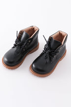 A pair of black faux leather booties with lace-up fronts and brown soles.
